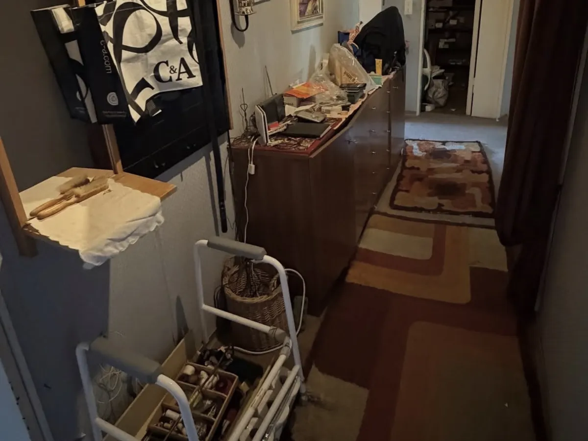 Flur vor der Entrümpelung: Garderobe, Kommode voller Sachen, Teppiche und Rollator
